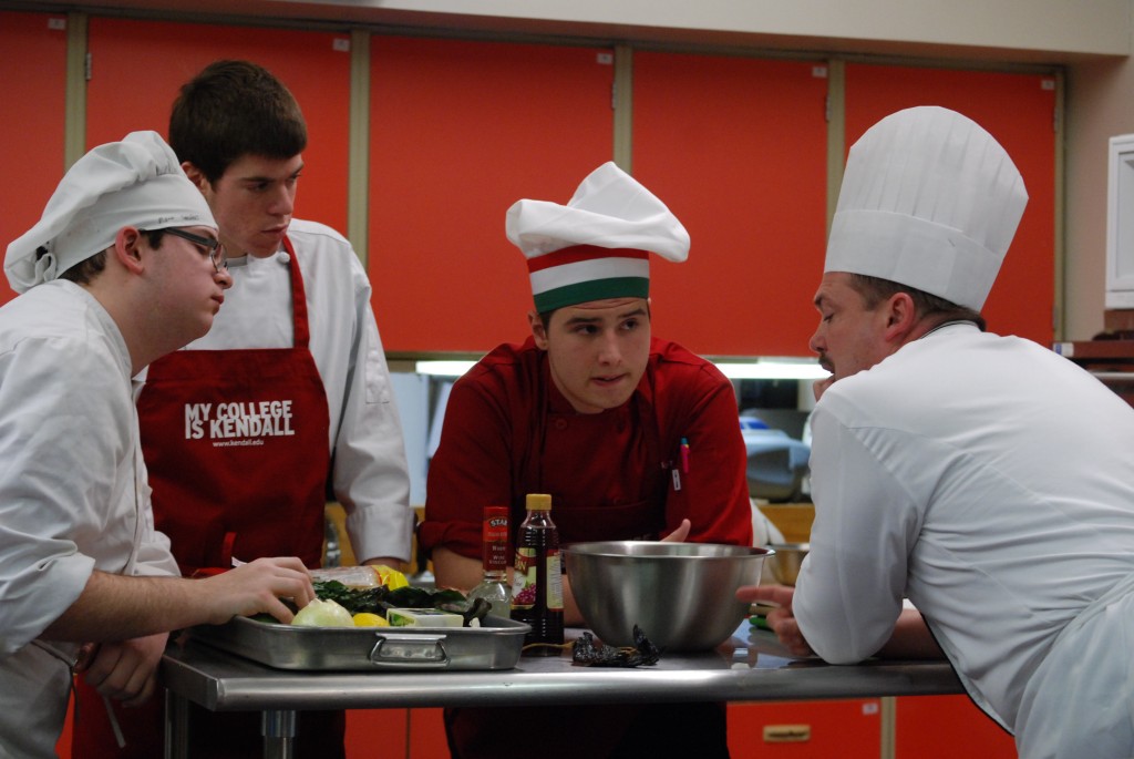 Seniors Matt Sanders, Brian Peoples and Nick Ceriotti discuss their dish with the vice president of Kendall College's culinary arts program at the Cook-Off on March 6. Photo by Emily Schenberg.