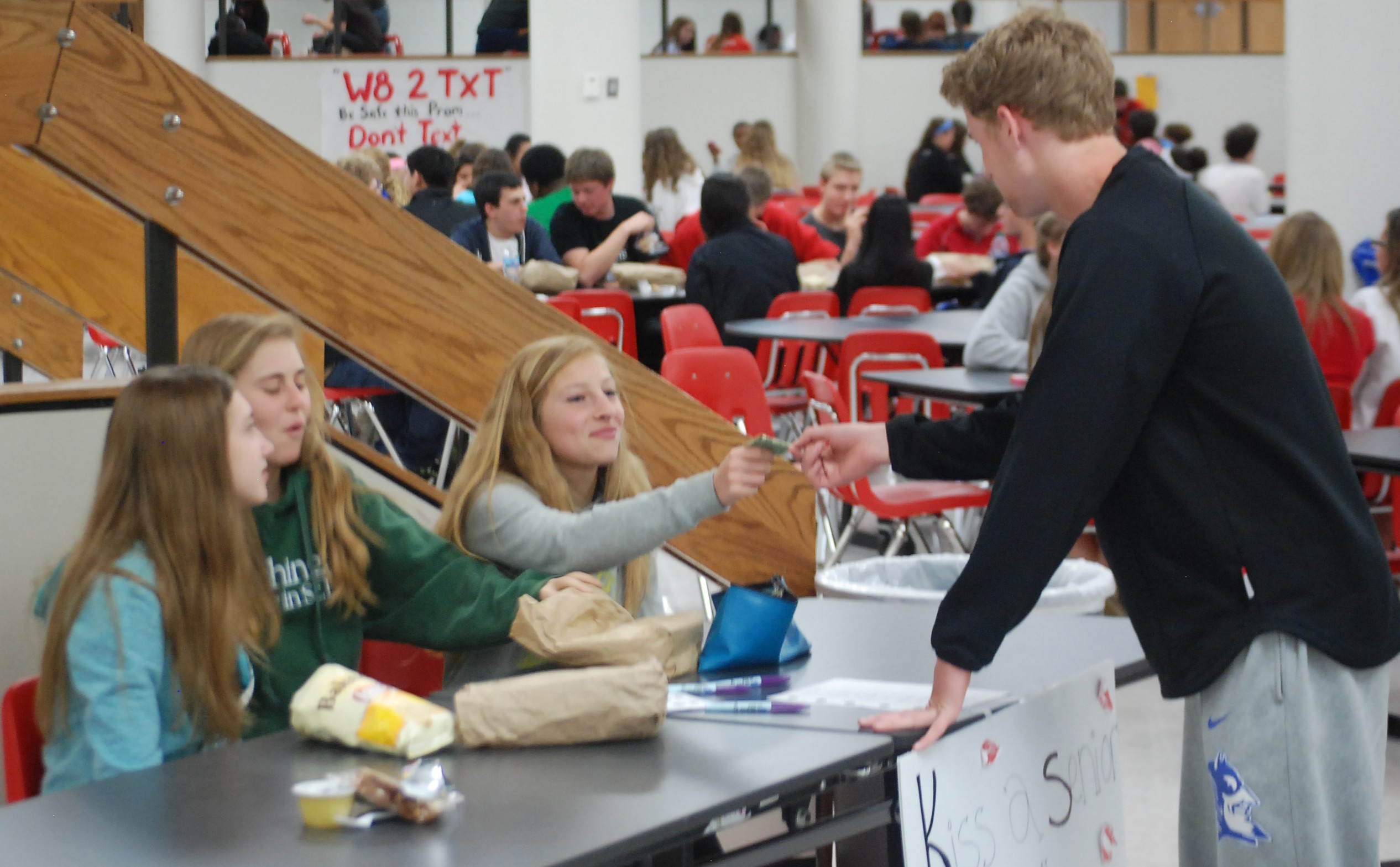 Freshman Michael Rembold buys a Hershey's kiss gram for the seniors during second lunch. They are being sold for $.50 each in the commons during lunch and students may include a personal message. Photo by Brandon Weissman.