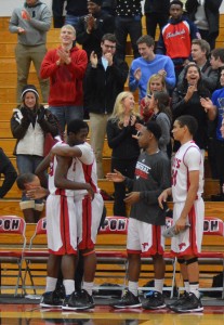 Senior Jarrett Cox-Bradley celebrates with teammates freshman DeAndre Campbell and senior Risaan McKenney and a standing ovation from the home crowd after he scored his 30th point of the game to reach exaclty 1,000 points on his career. Photo by Erin Friesen.